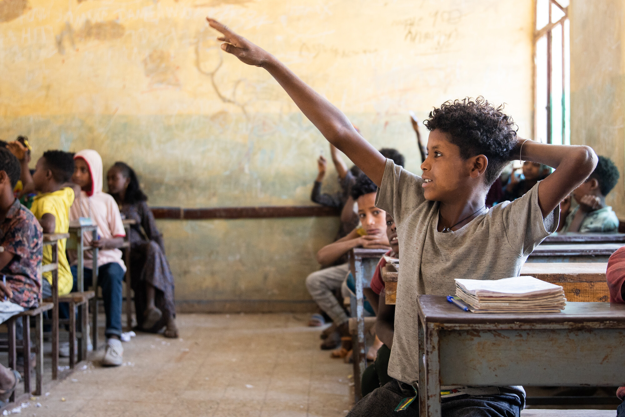 Biruk, 14, raises his hand in class at a school affected by conflict in Kobo District. During the Tigray War, the school was used as a camp by both warring parties and much of it was destroyed by gunfire. Today, ChildFund is helping rebuild.