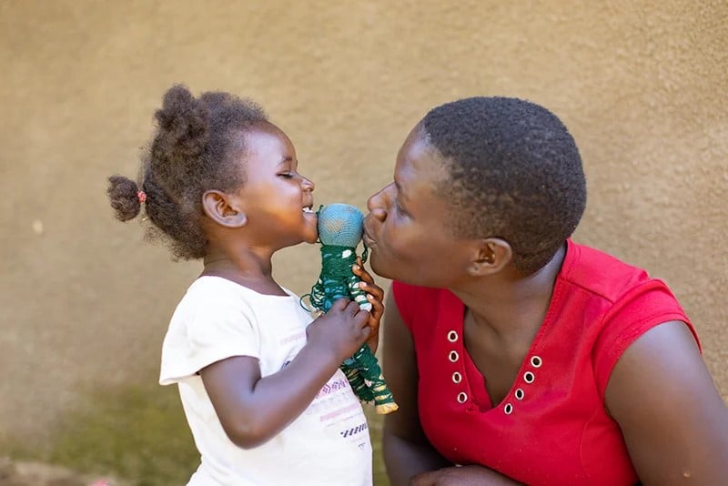 Mother and daughter sharing a loving moment with a handmade doll, symbolizing care and connection.