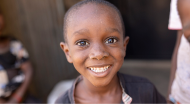 Smiling young boy looking at the camera, representing joy and hope for the future.