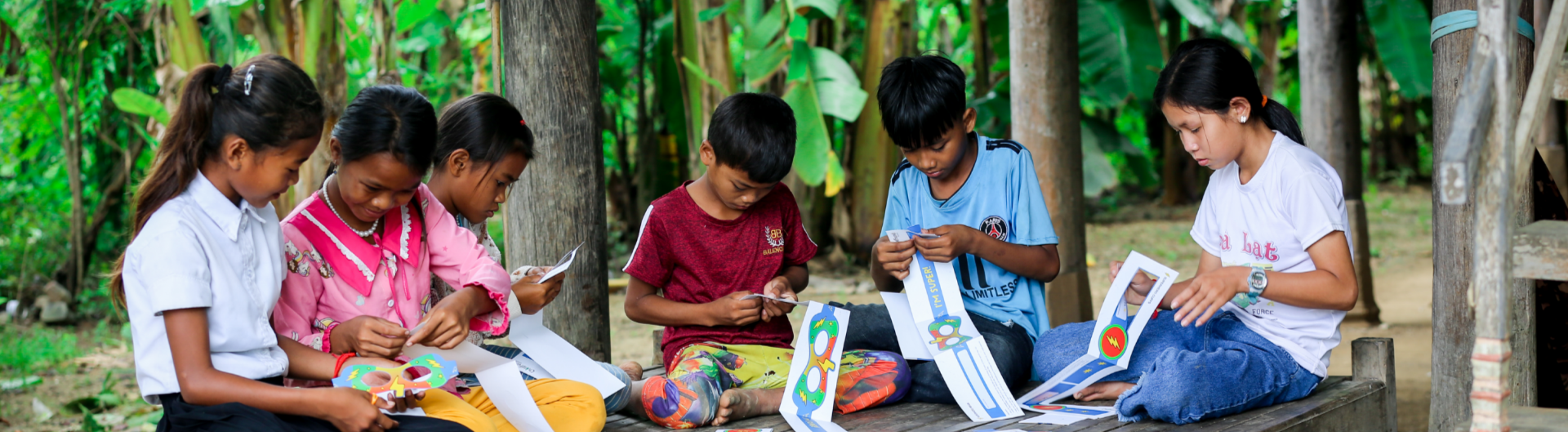 A group of children in a rural setting play with arts and crafts.