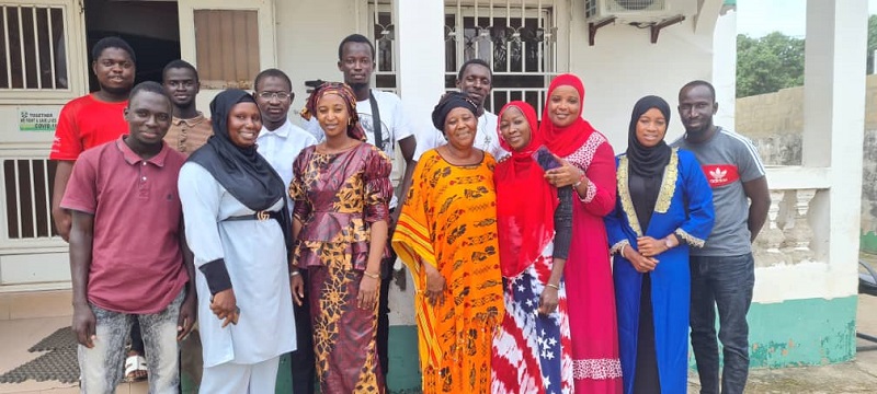 A group of teachers in The Gambia pose for a photo outside in front of a school.
