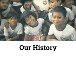 Group of smiling children in school uniforms with "Our History" text below, representing community and education.